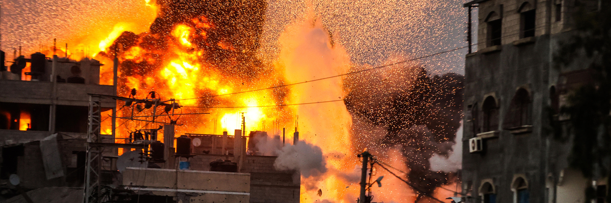Rauch und Flammen am dunklen Himmel über zerstörtem Haus in Gaza