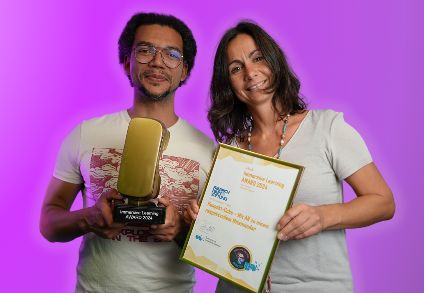 Zwei Personen des Teams Digitale Bildung des FES mit dem Immersive Learning Award und mit dem Respekt-Cube in der Hand
