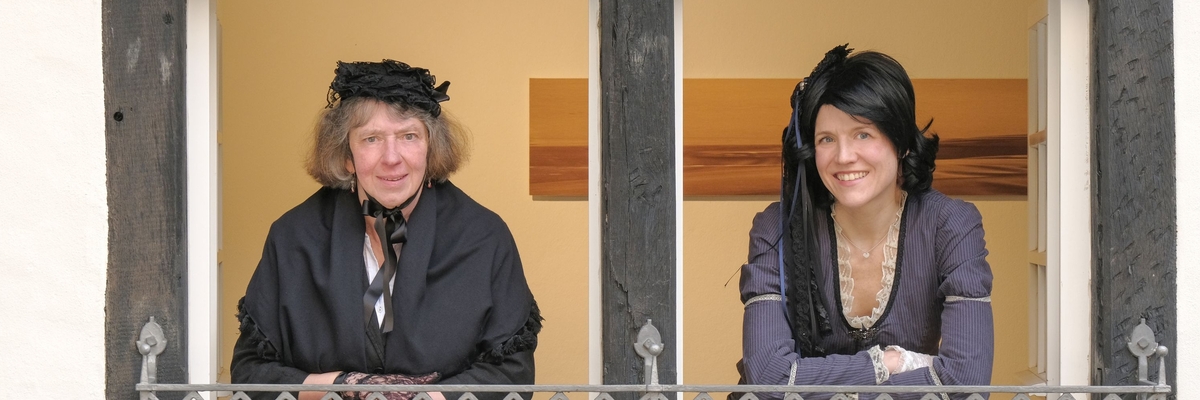 Die beiden Kostümführerinnen schauen als Jenny von Westphalen verkleidet aus dem Fenster. 
