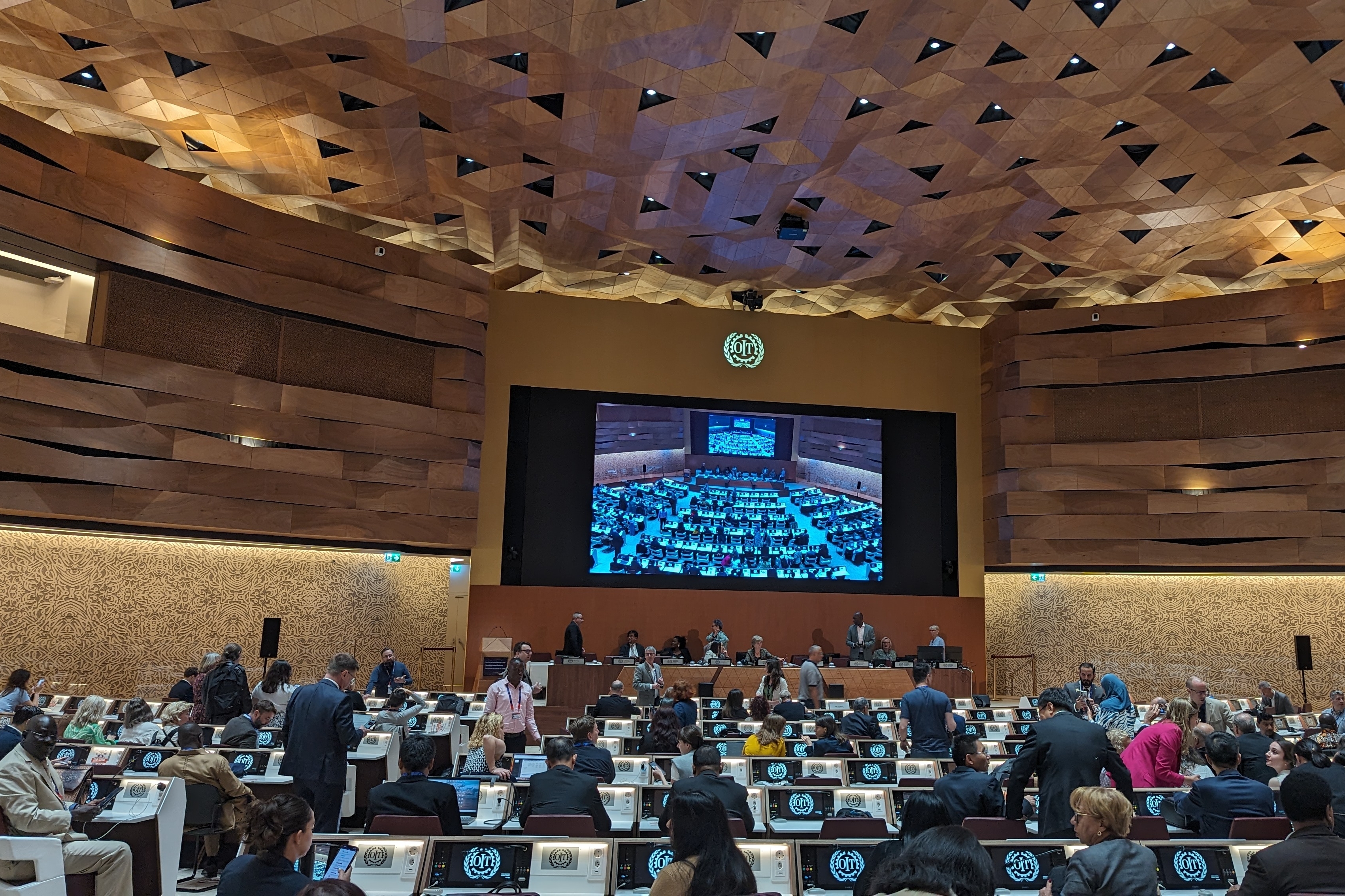 Plenarsaal XIX der Vereinten Nationen in Genf. Im Vordergrund die Sitzreihen und im Hintergrund das Plenum.