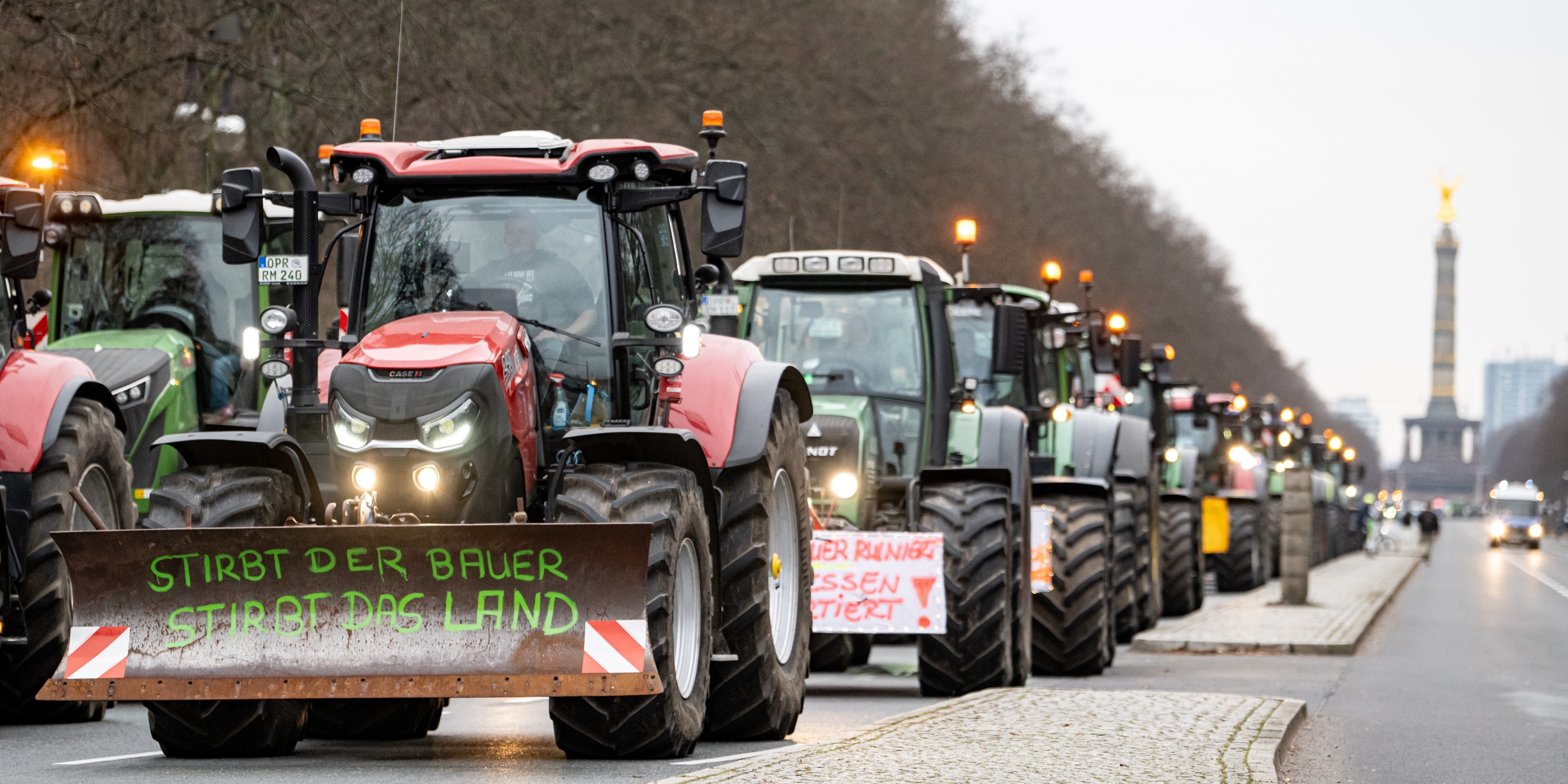 Eine Reihe Traktoren auf einer Demo auf der Straße des 17. Juni in Berlin, der erste trägt die Aufschrift "Stirbt der Bauer, stirbt das Land"