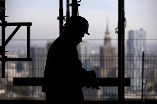 The Palace of Culture is seen behind a worker at a construction site in Warsaw.