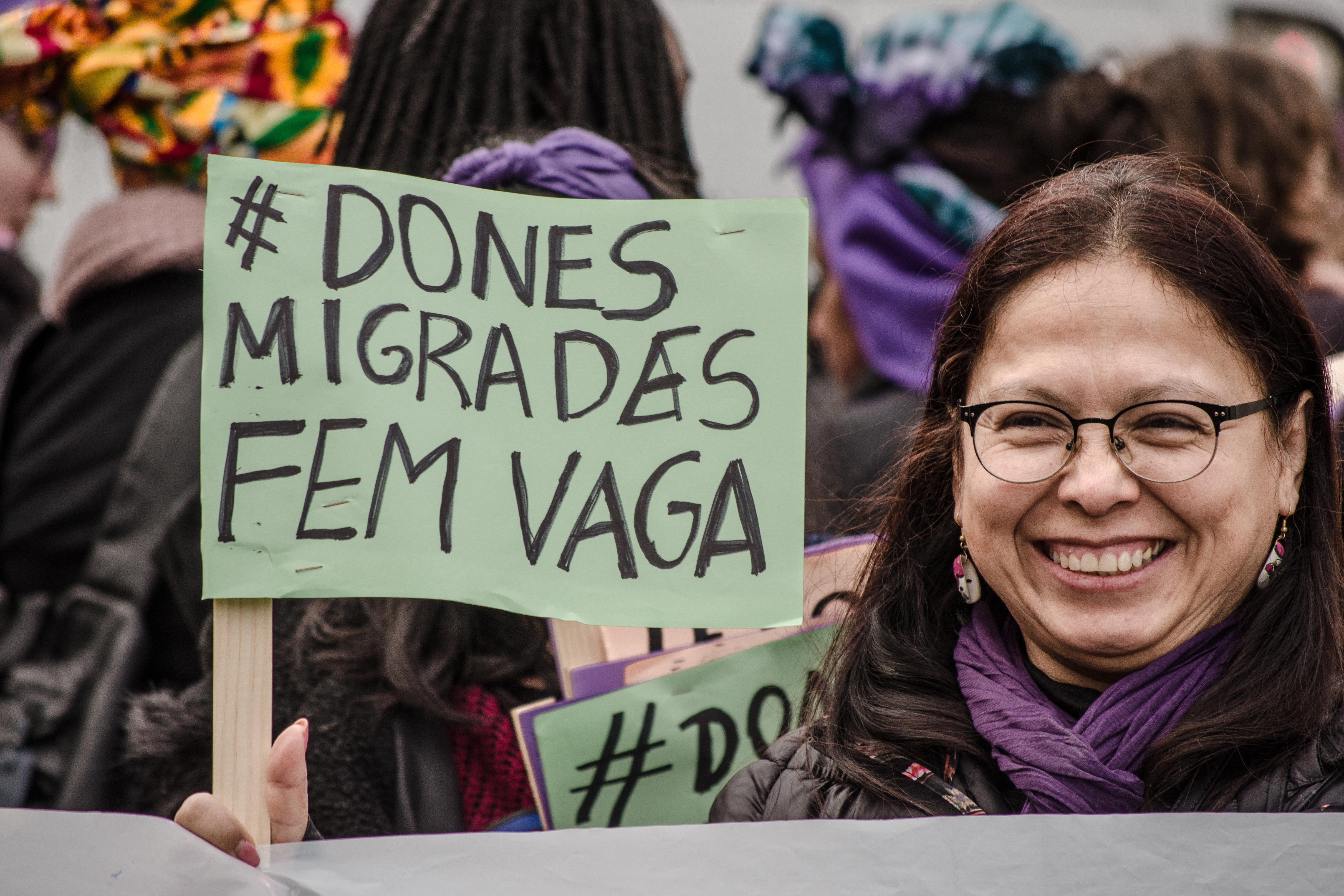 Eine Demonstrantin zeigt ein Plakat, das sich auf streikende Migrantinnen bezieht. Auf dem Plakat steht "Dones Migrades Fem vaga", "Migrantinnen in Bewegung".