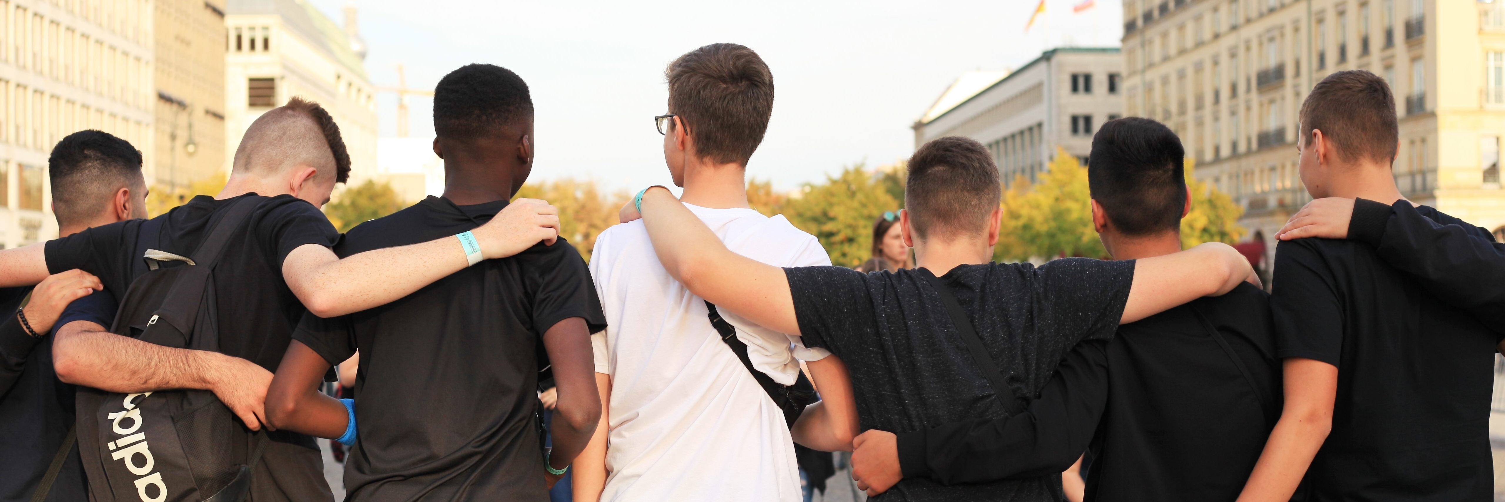 Jungen, die zu einer Sportmannschaft gehören, stehen gemeinsam am Brandenburger Tor, um Fotos zu machen. Einige von ihnen haben Migrationshintergrund, andere nicht. 