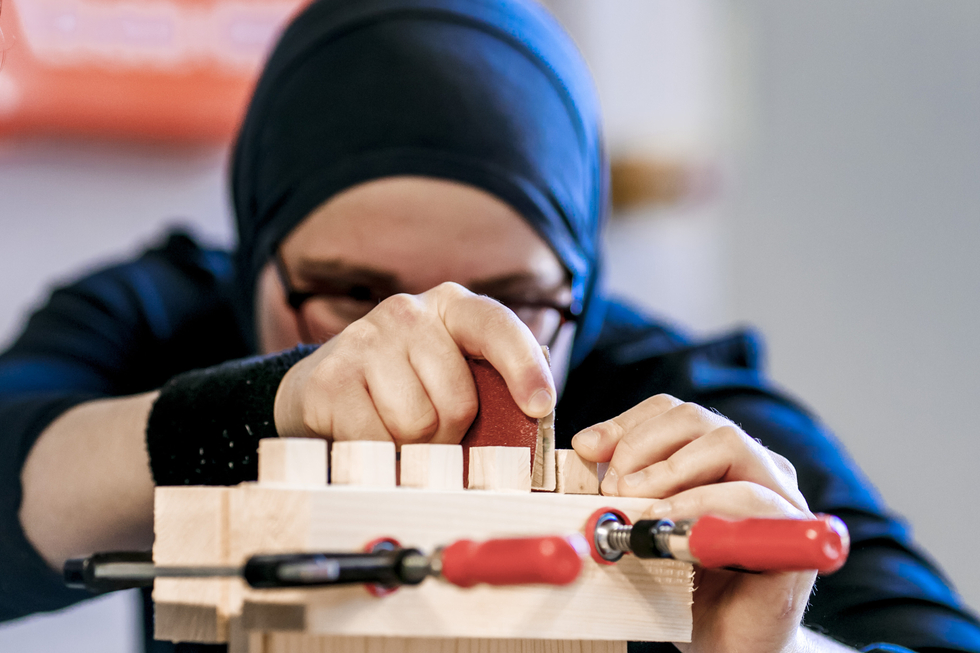 Eine geflüchtete Frau mit Kopftuch arbeitet in der Übungswerkstatt für Handwerksausbildung.