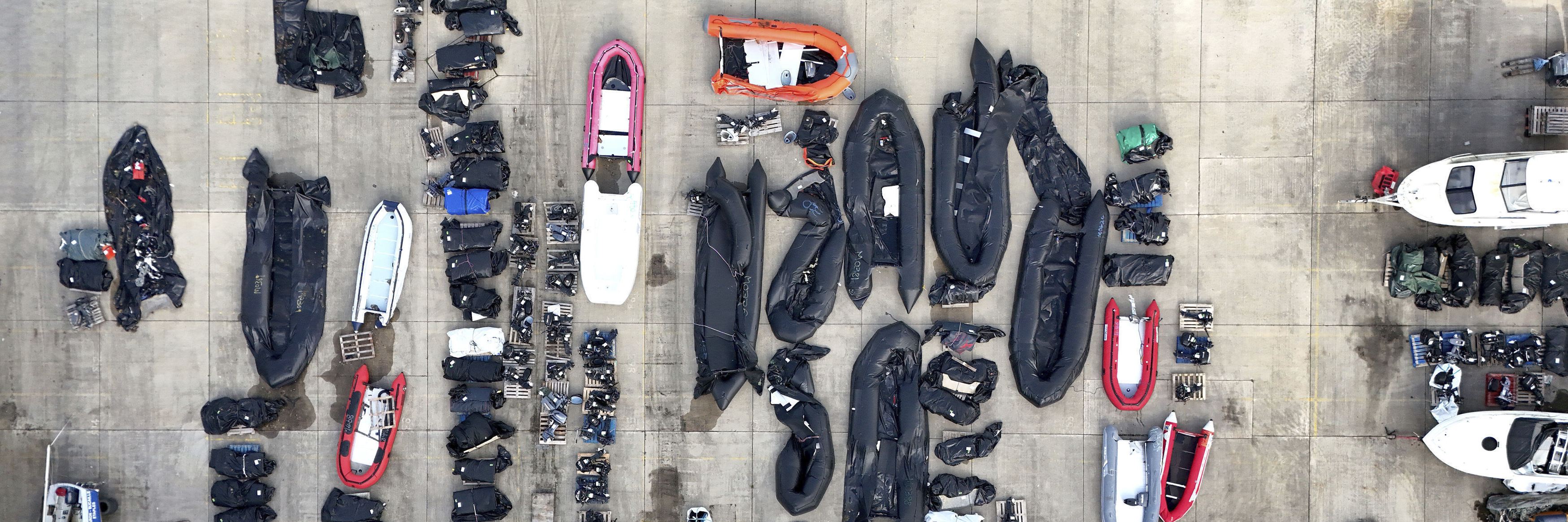 Luftansicht von einer Reihe an Schlauchbooten und Außenmotoren an einem Hafen