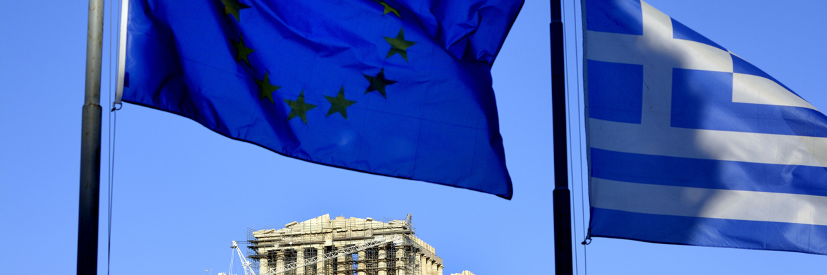 A Greek flag and an EU flag fly at the Acropolis in Athens