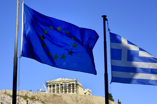 A Greek flag and an EU flag fly at the Acropolis in Athens